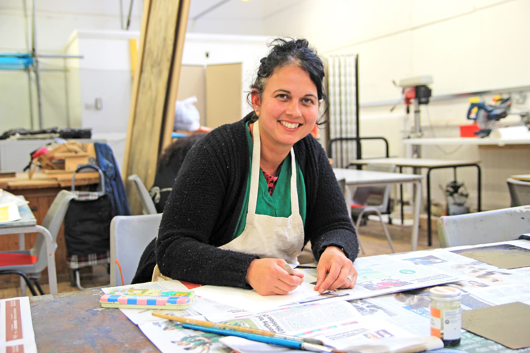 A part time leisure student looks at the camera and smiles. They look to be taking part in a creative class.