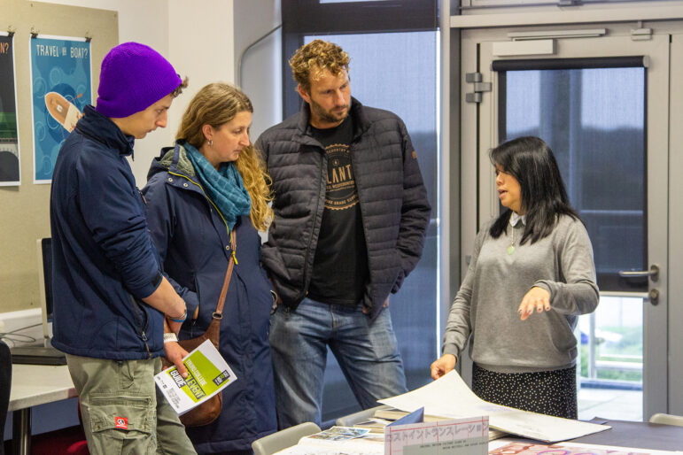 Openevent A student visits an open event with their parents. They stand and talk to a tutor. There is an open event guide in the student's hand.