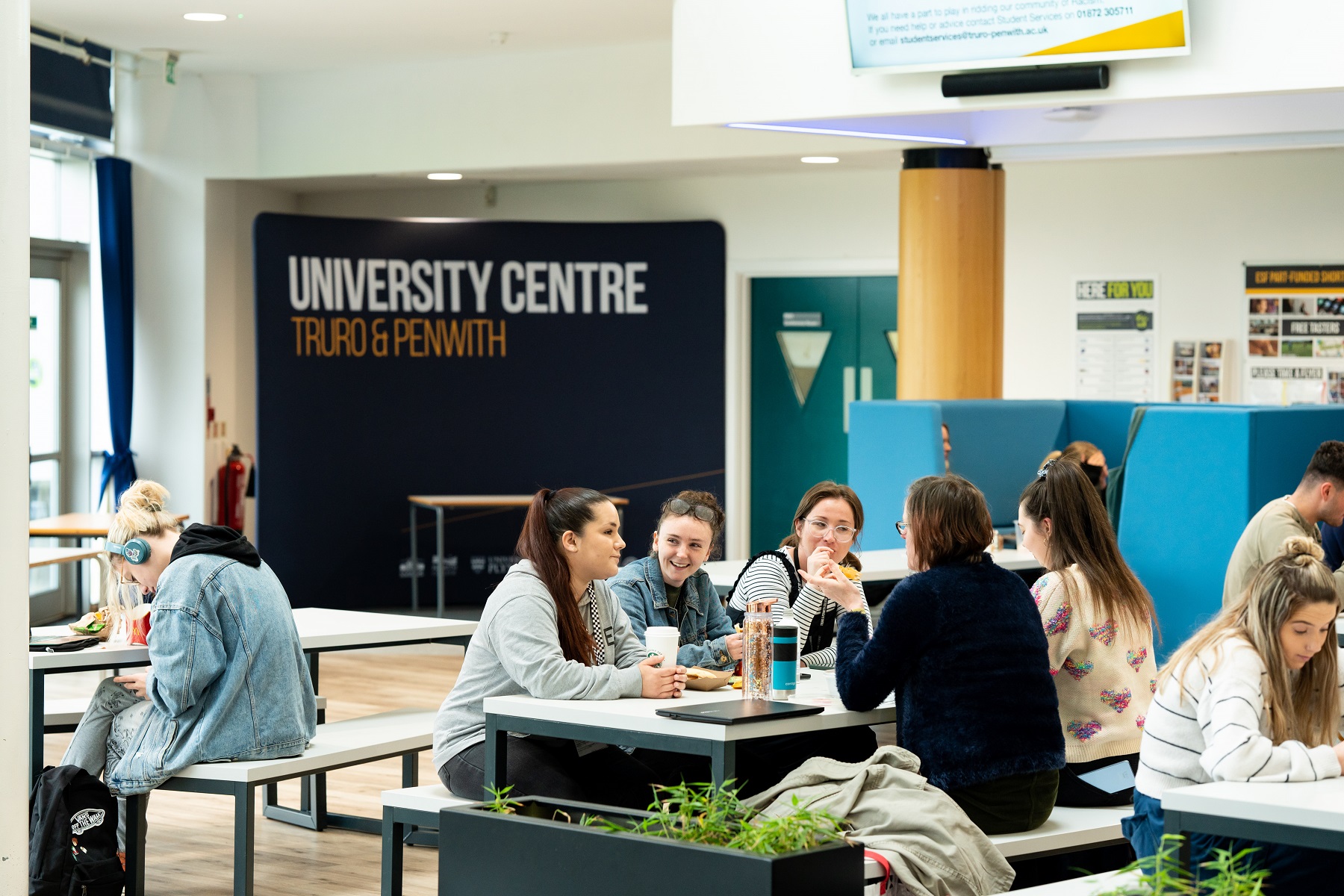 General HE 0009 A group of adult students sit at a table in the Fal building chatting and enjoying drinks.