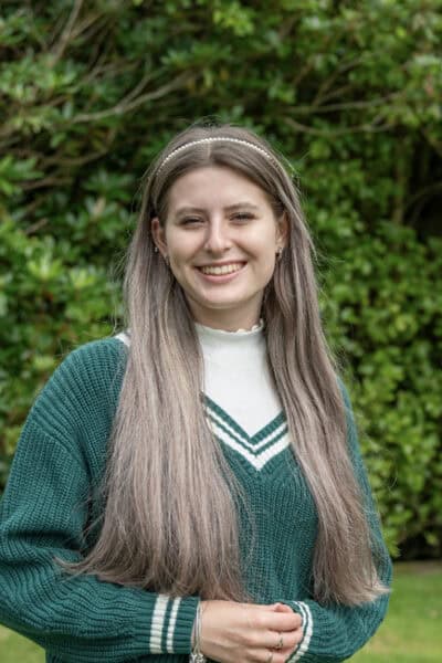 Milarna Milarna stands outside wearing a green jumper smiling at the camera.